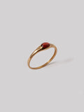 Gold ring with a red stone on a light gray background