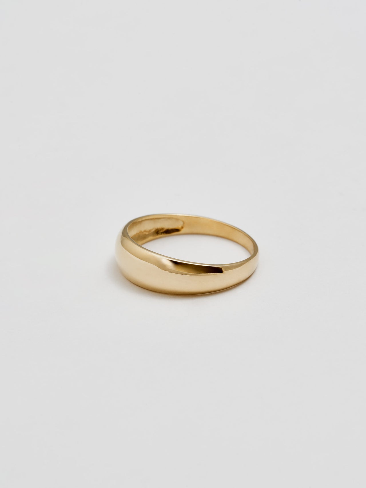 Product shot of the side of Baby Dome Ring (shiny 14Kt Yellow Gold Dome Ring Tapered Width) with white background.