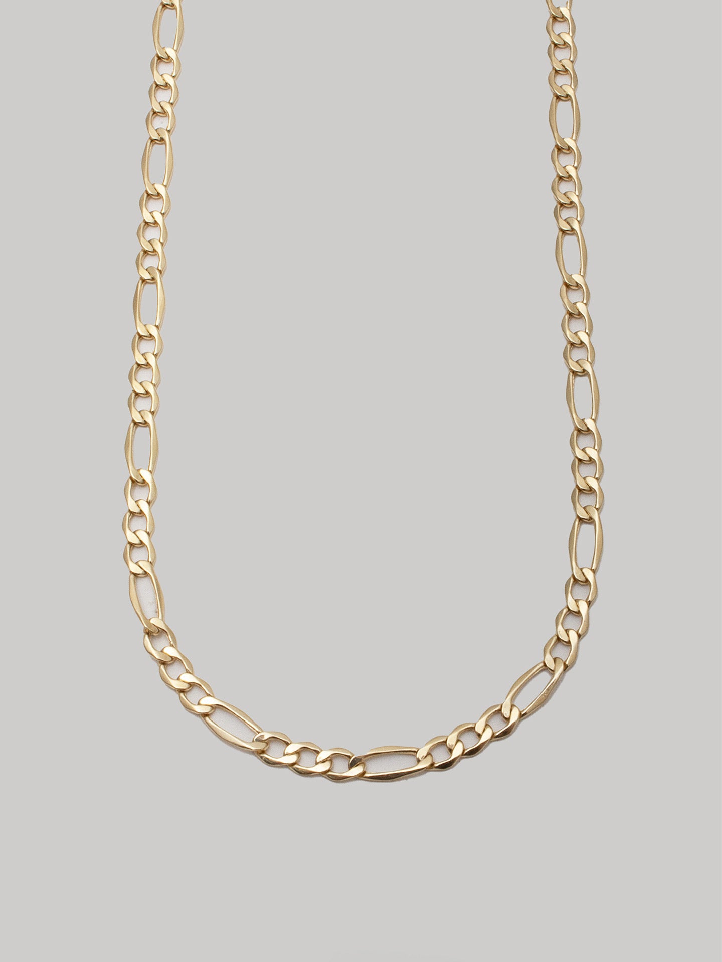 14kt Yellow Gold Hollow Figaro Chain Necklace pictured close up on light grey background. 
