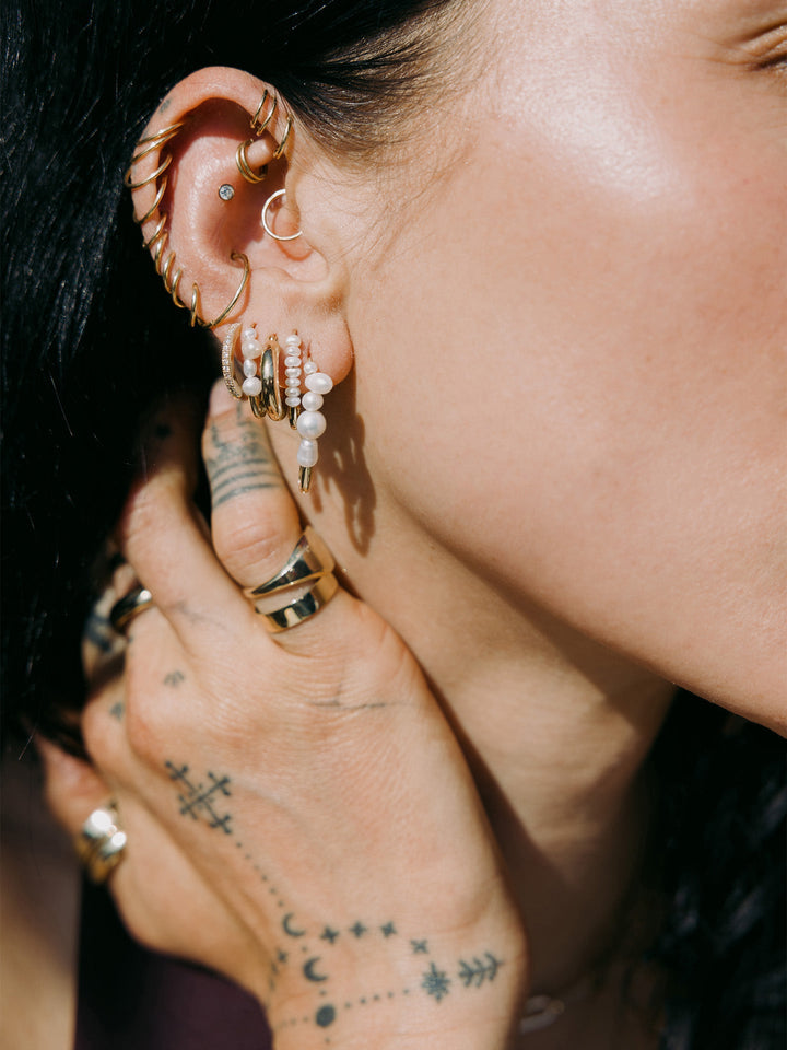 Baby Sol Hoops pictured in models third piercing. Styled with other best selling earrings. 
