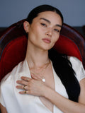 Square & Toggle necklace pictured on model sitting in red velvet chair. 