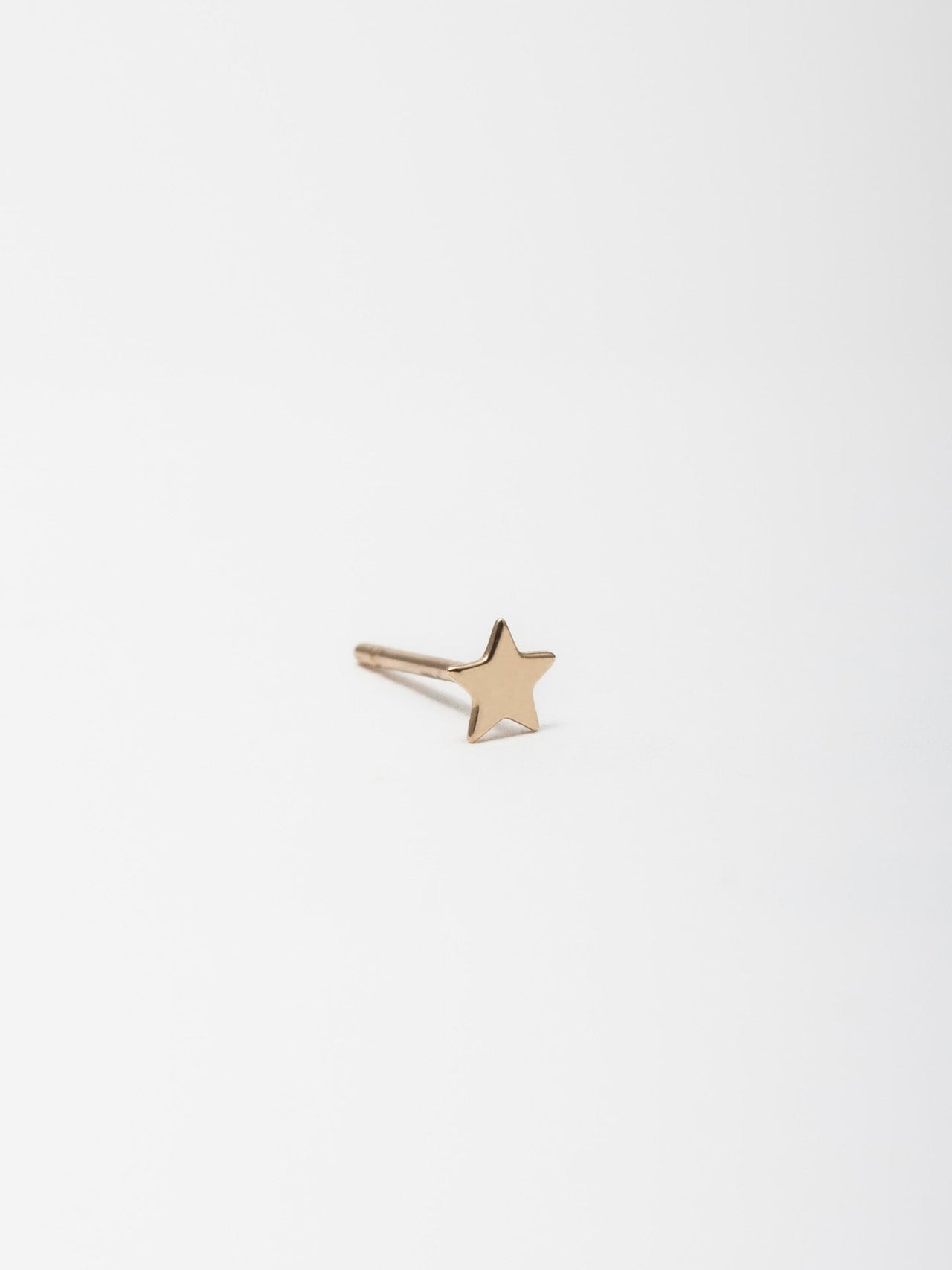 14kt Yellow Gold Mini Star Stud pictured on light grey background 