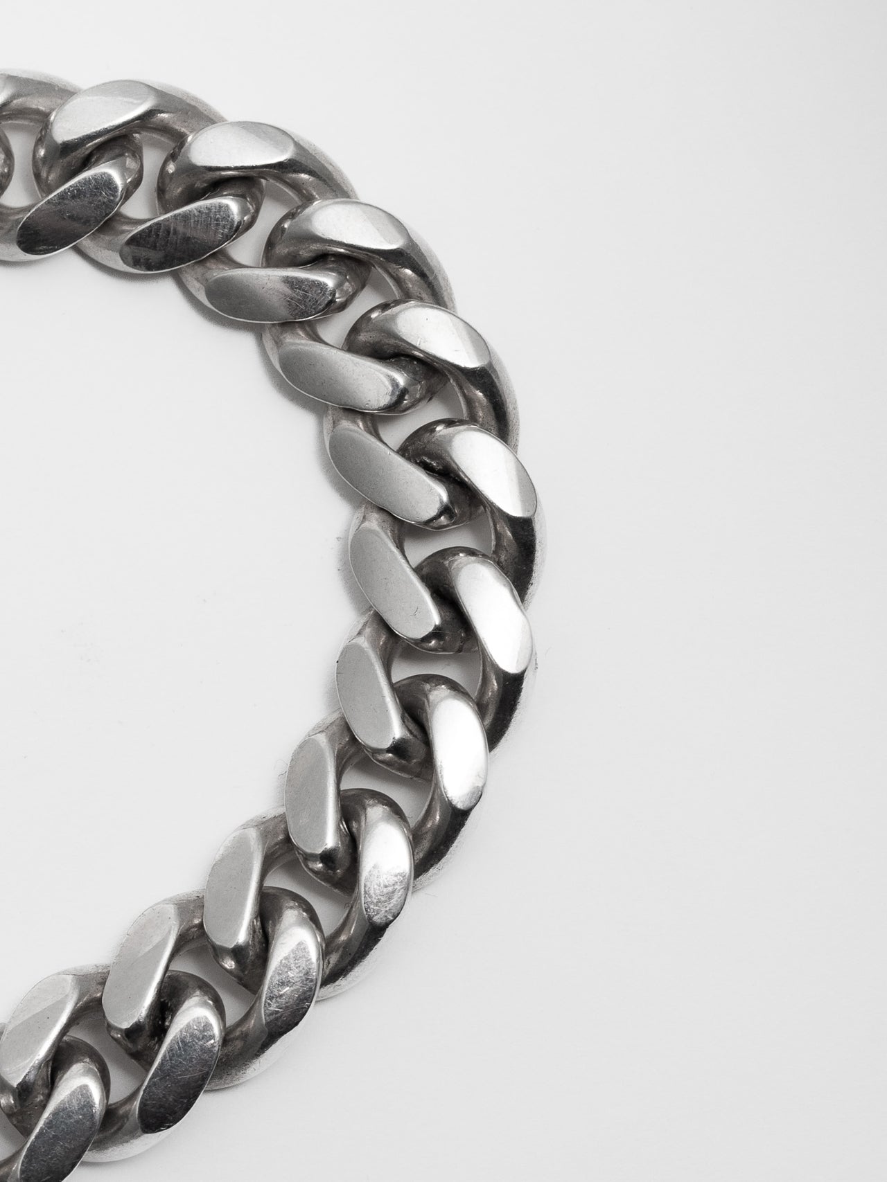 Close up of Sterling Silver XL Curb Chain Bracelet on light grey background.