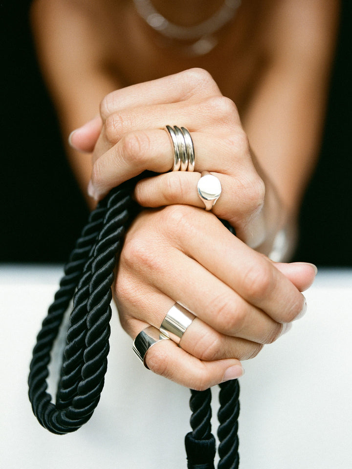 Close up of Sterling Silver XL Hug Band on models hand. Black background. 