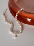 14kt Yellow Gold Boujee Pearl Strand pictured laying on surface next to orange glass catchall. 