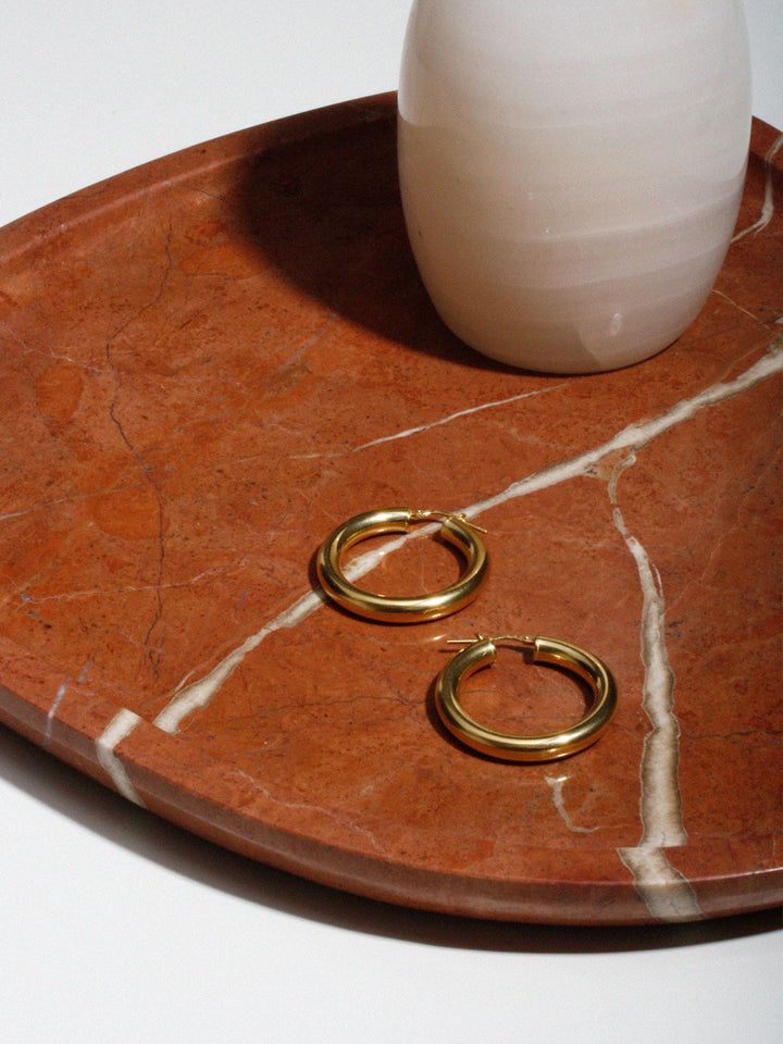 Vermeil Tube Hoops pictured on marble tray. 