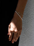 Hand wearing a bracelet against a dark background