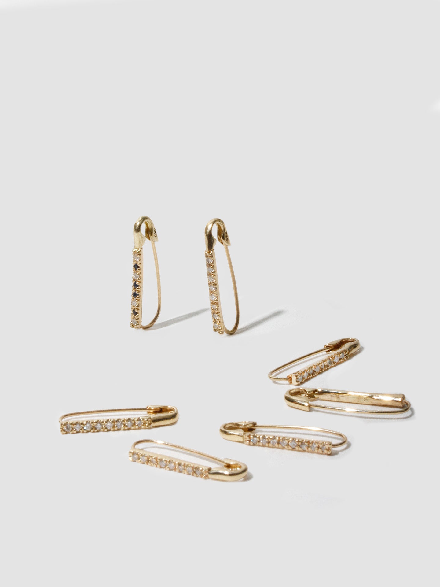 14kt Yellow Gold Mini Diamond Safety Pin pictured on light grey background. 