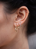 14kt Yellow Gold CZ Huggie pictured on models ear in third piercing. 