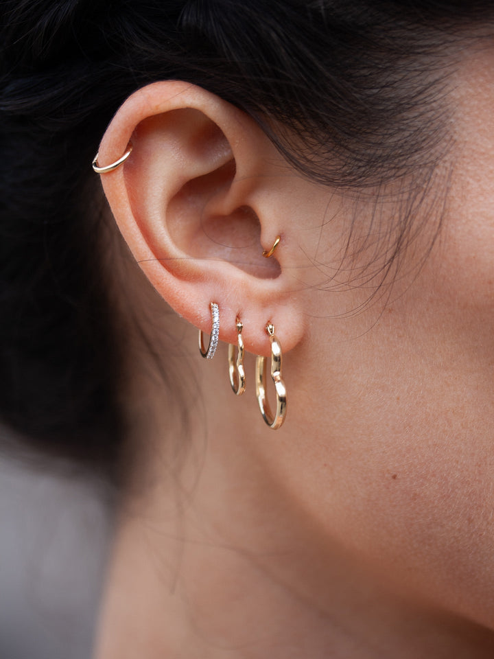 14kt Yellow Gold CZ Huggie pictured on models ear in third piercing. 