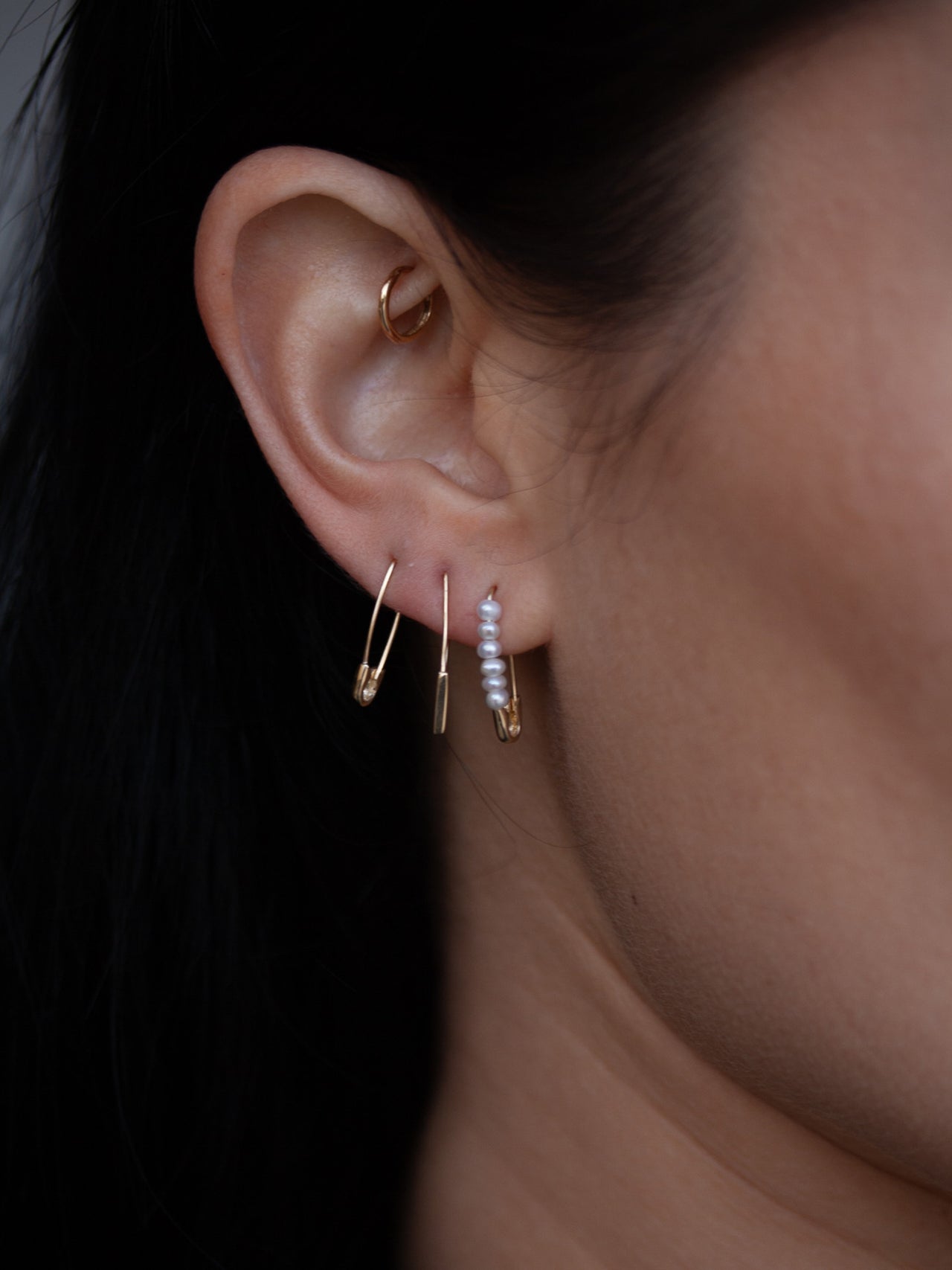 Mini Friendship Safety Pin Earring pictured in models first piercing.  Stacked with other safety pin earrings.