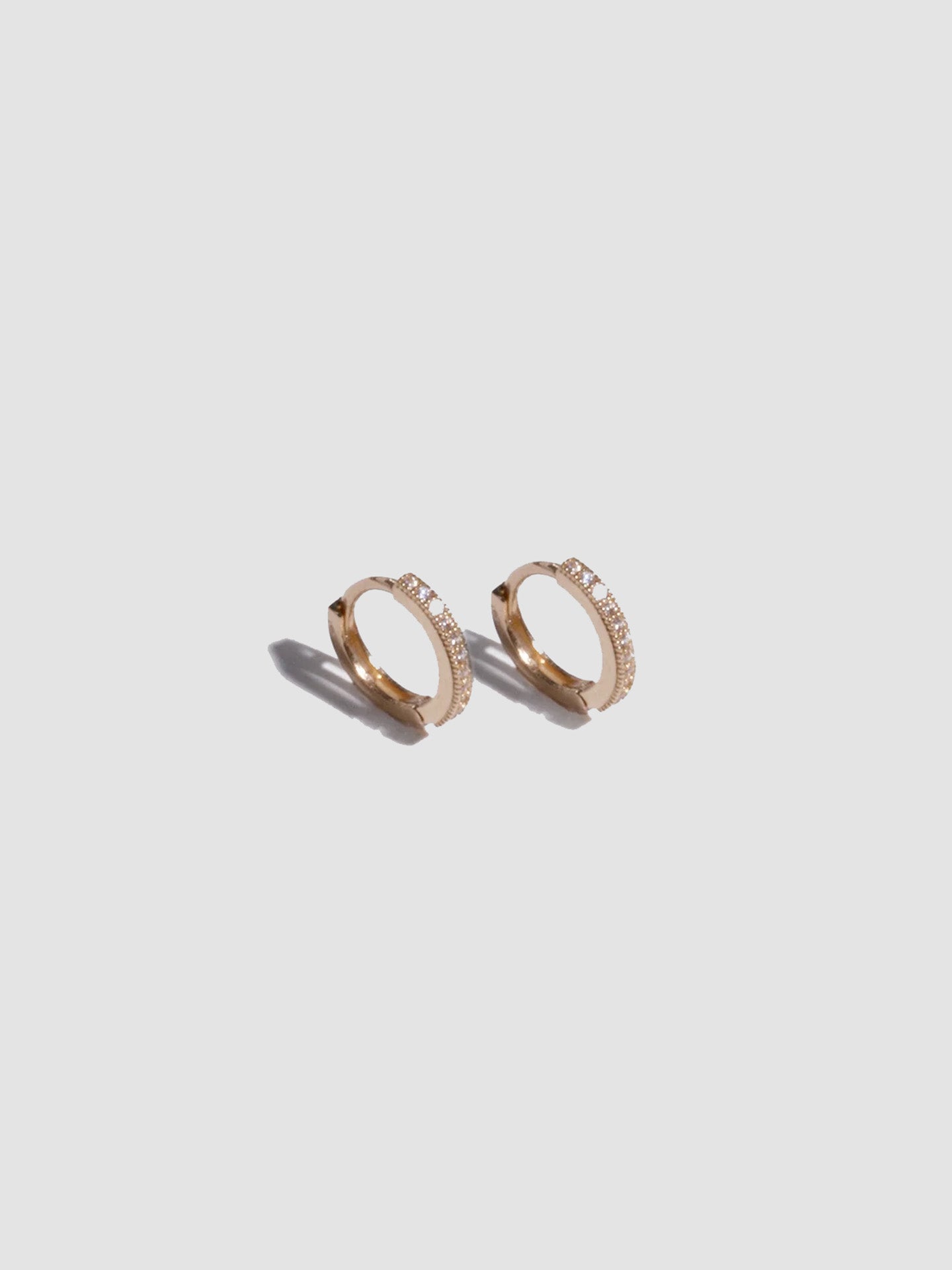 Pair of gold hoop earrings on a light gray background