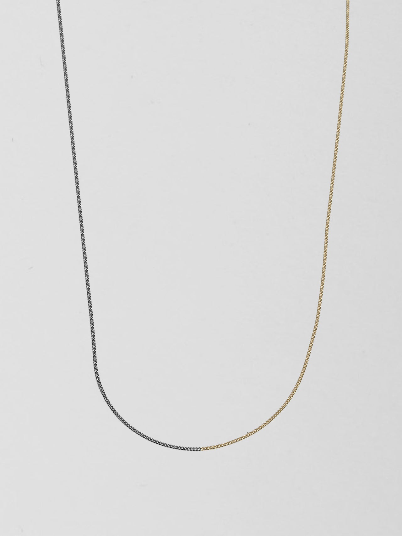 Half 14kt Yellow Gold & Half Oxidized Sterling Silver Curb Chain Necklace pictured on light grey background.