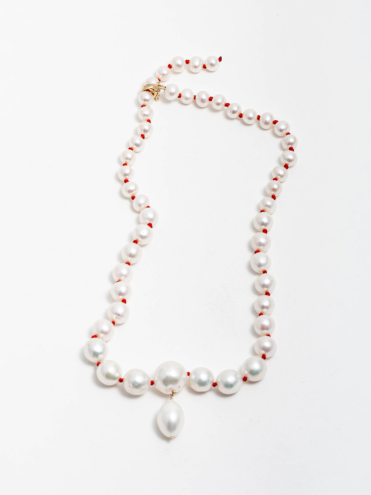 14kt Yellow Gold Boujee Pearl Necklace with Hand Knotted Red Thread pictured on light grey background.