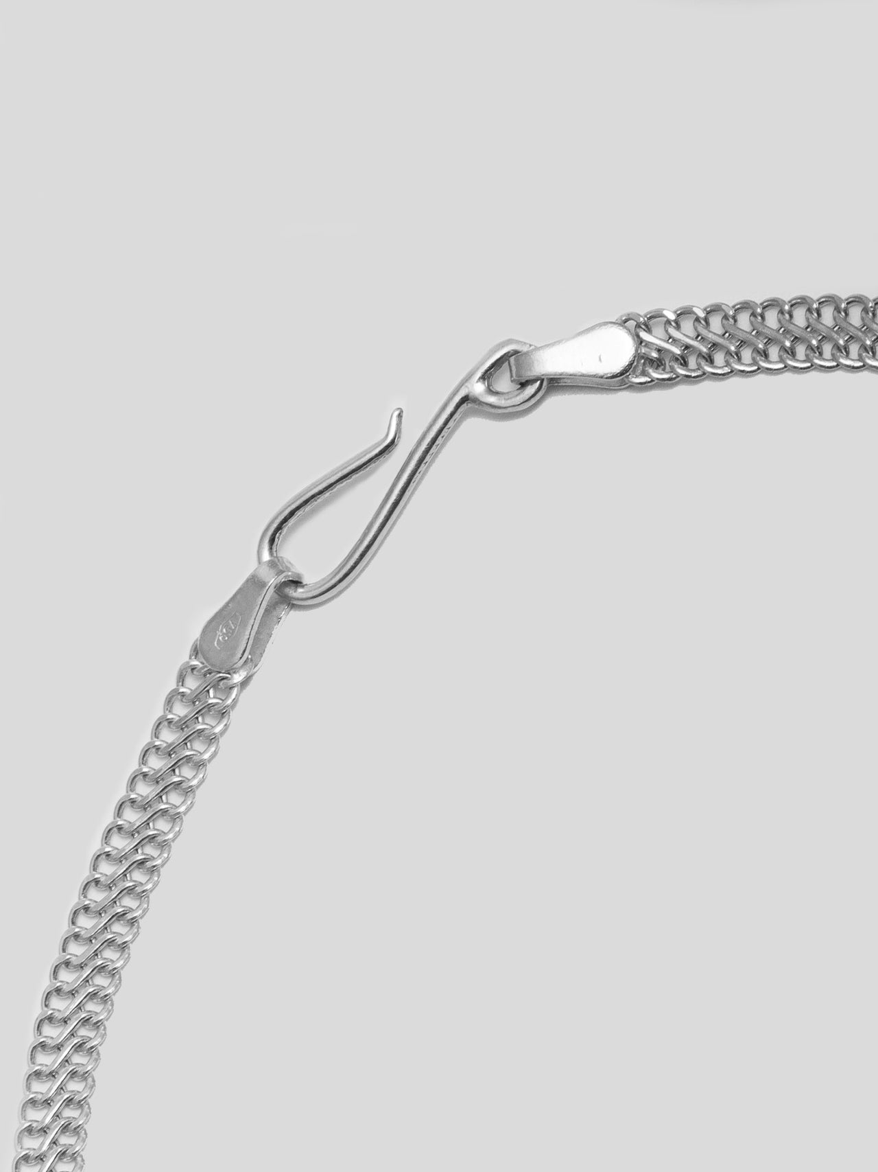 Close up of Sterling Silver Mesh Chain Bracelet hook closure. Light grey background.  