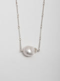 Close up of Sterling Silver Bar Link Chain & Pearl Necklace pictured on light grey background. 