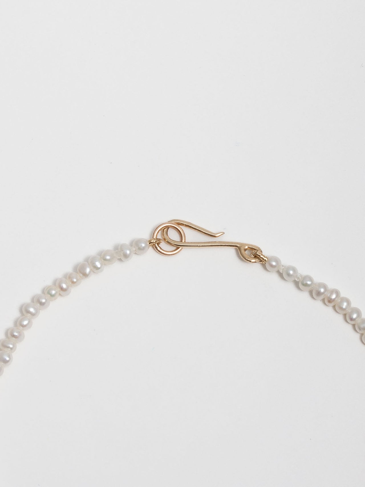 Close up shot of 14kt Yellow Gold Graduating Pearl Necklace's hook closure. 