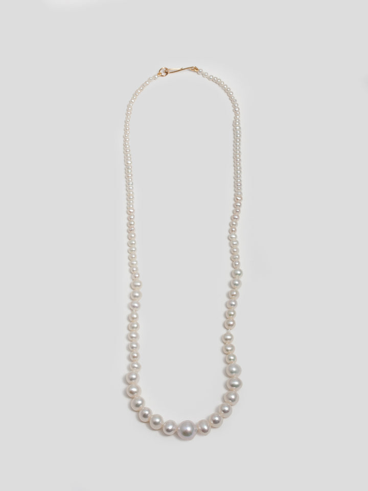 14kt Yellow Gold Graduating Pearl Necklace with hook closure pictured on light grey background. 