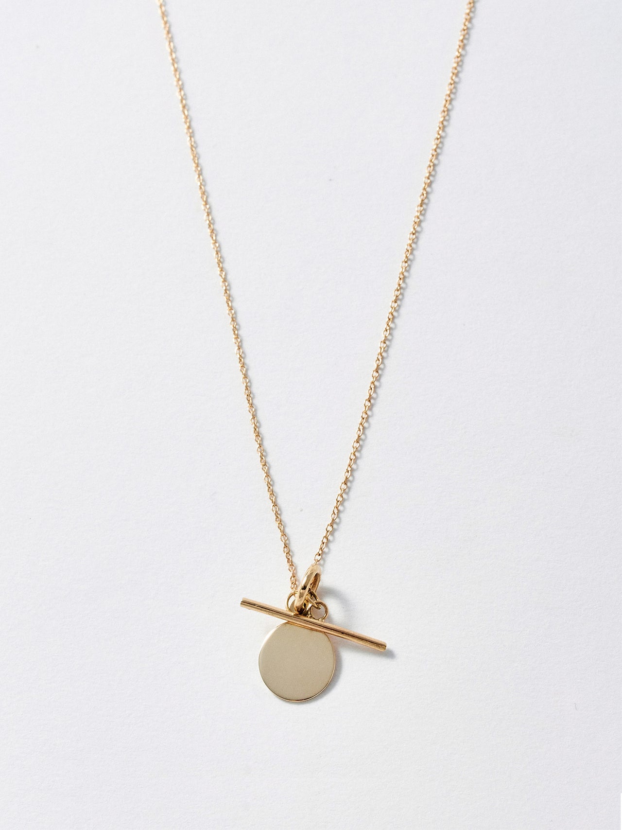 14Kt Yellow Gold Disk and Toggle Necklace pictured on light grey background.