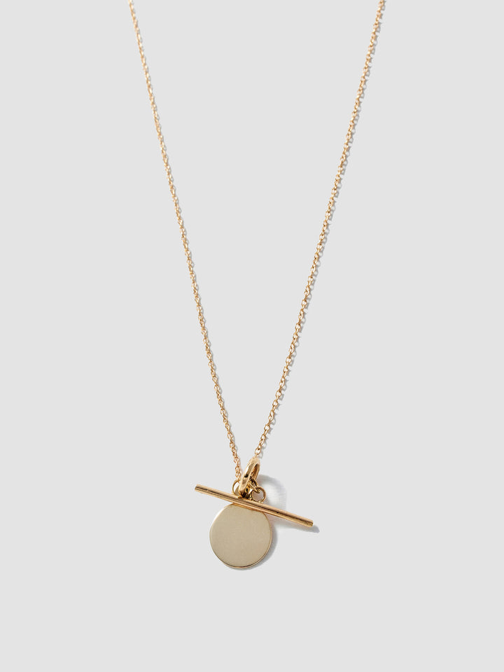 14Kt Yellow Gold Disk and Toggle Necklace pictured on light grey background.