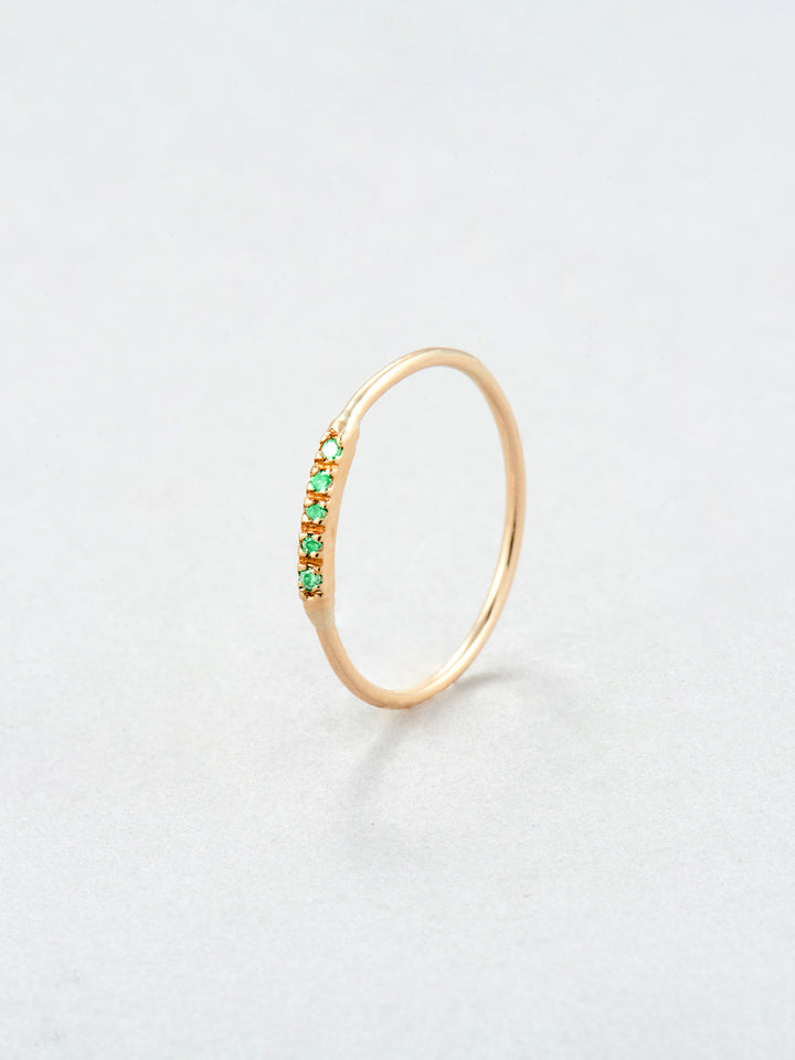 14kt Yellow Gold Emerald Baby Band pictured vertically on light grey background. 