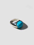 Silver ring with a turquoise stone on a light gray background