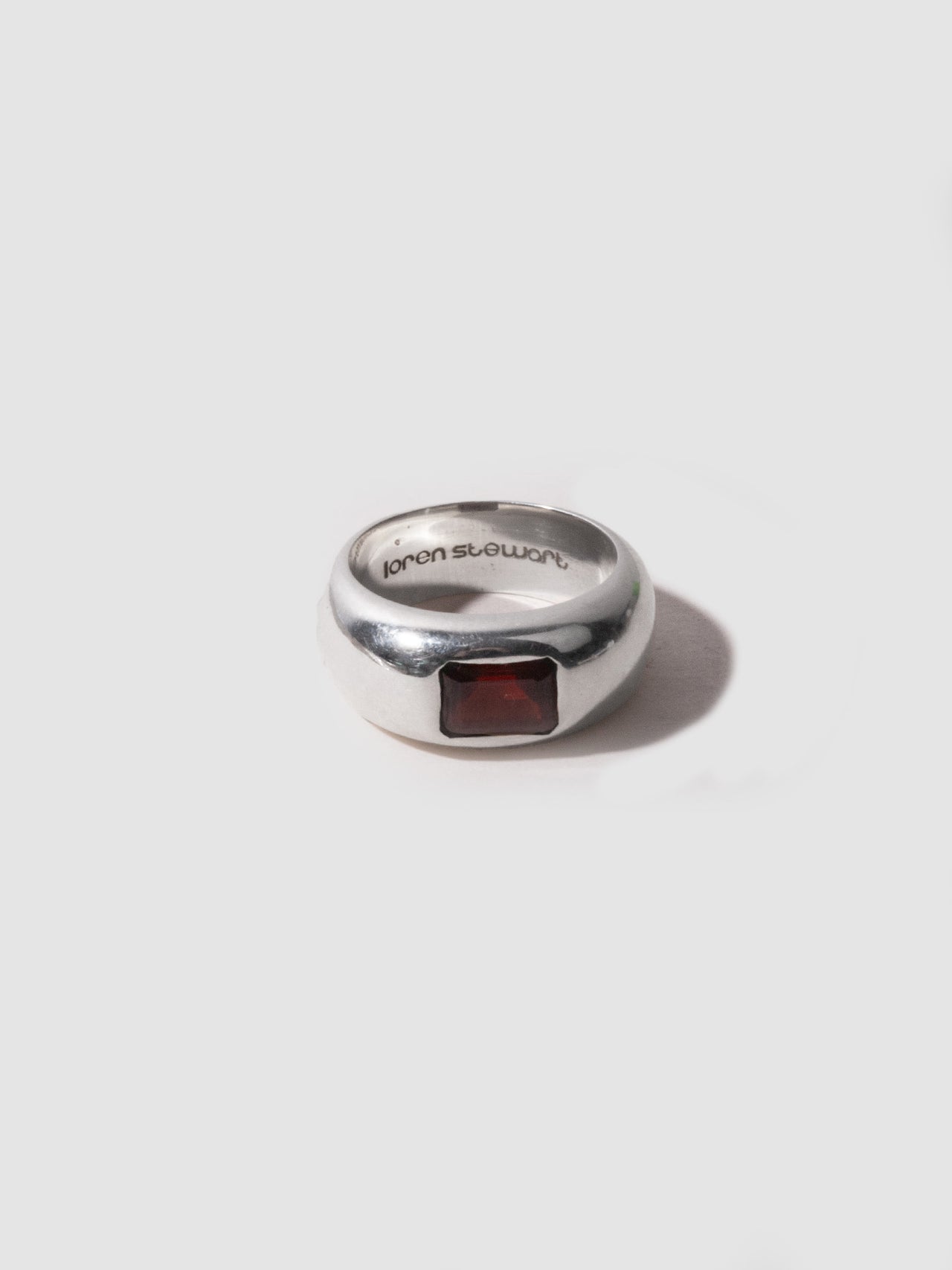 Silver ring with a red stone on a white background