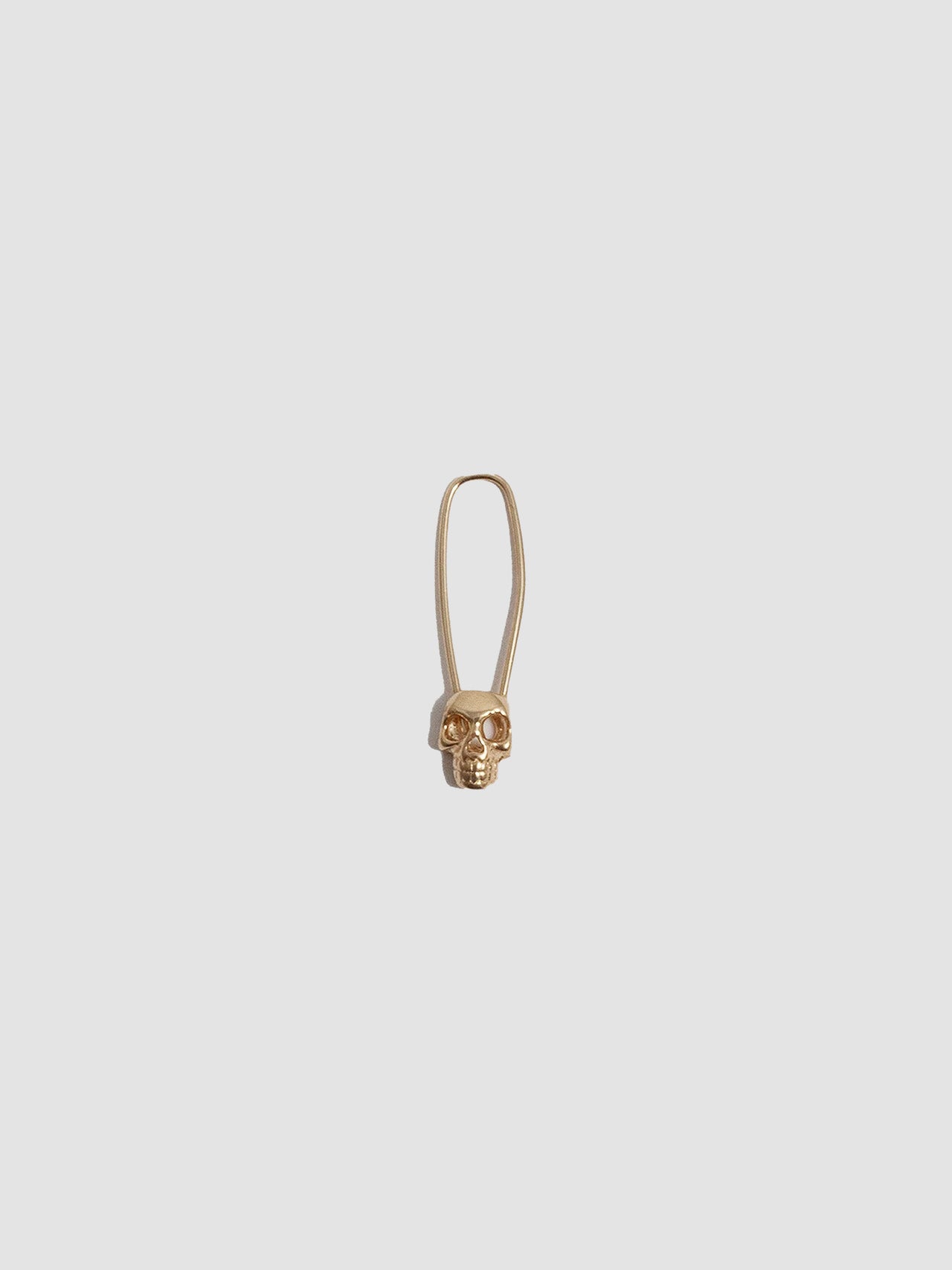Skull Safety Pin earring on light grey background.