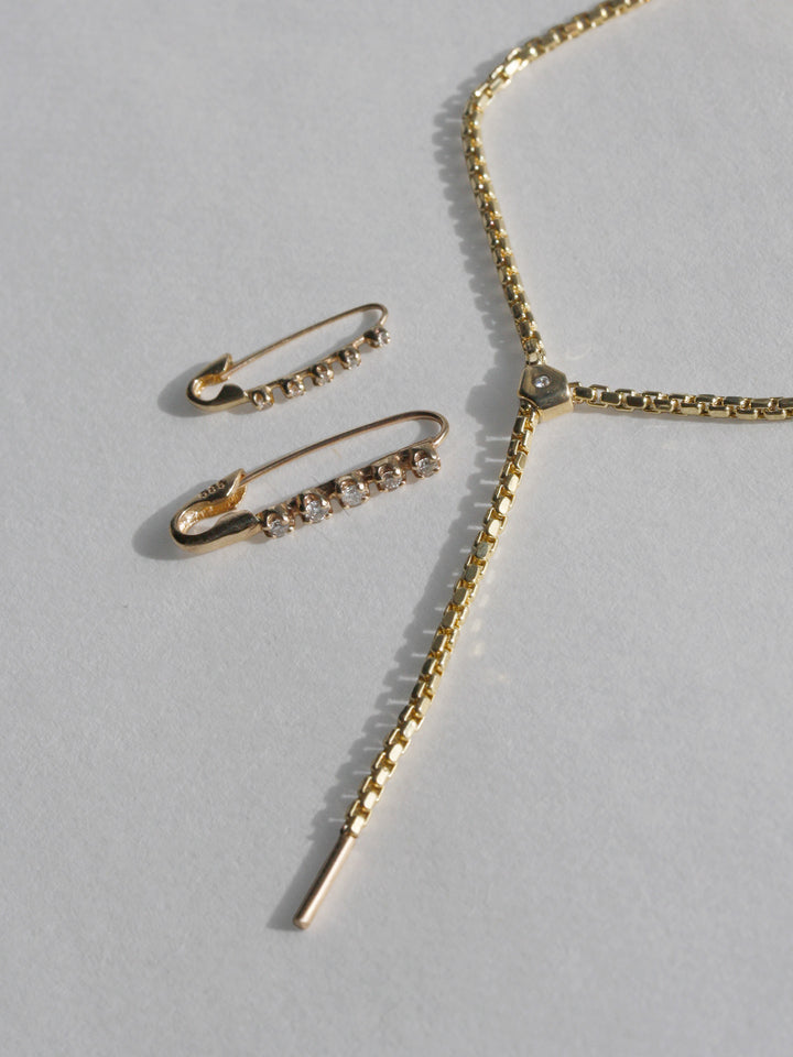 Gold necklace and earrings on a light gray background