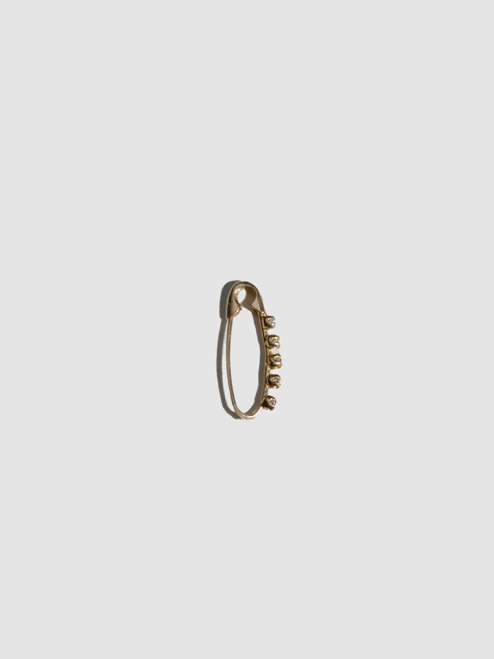 Gold safety pin earring on a light gray background