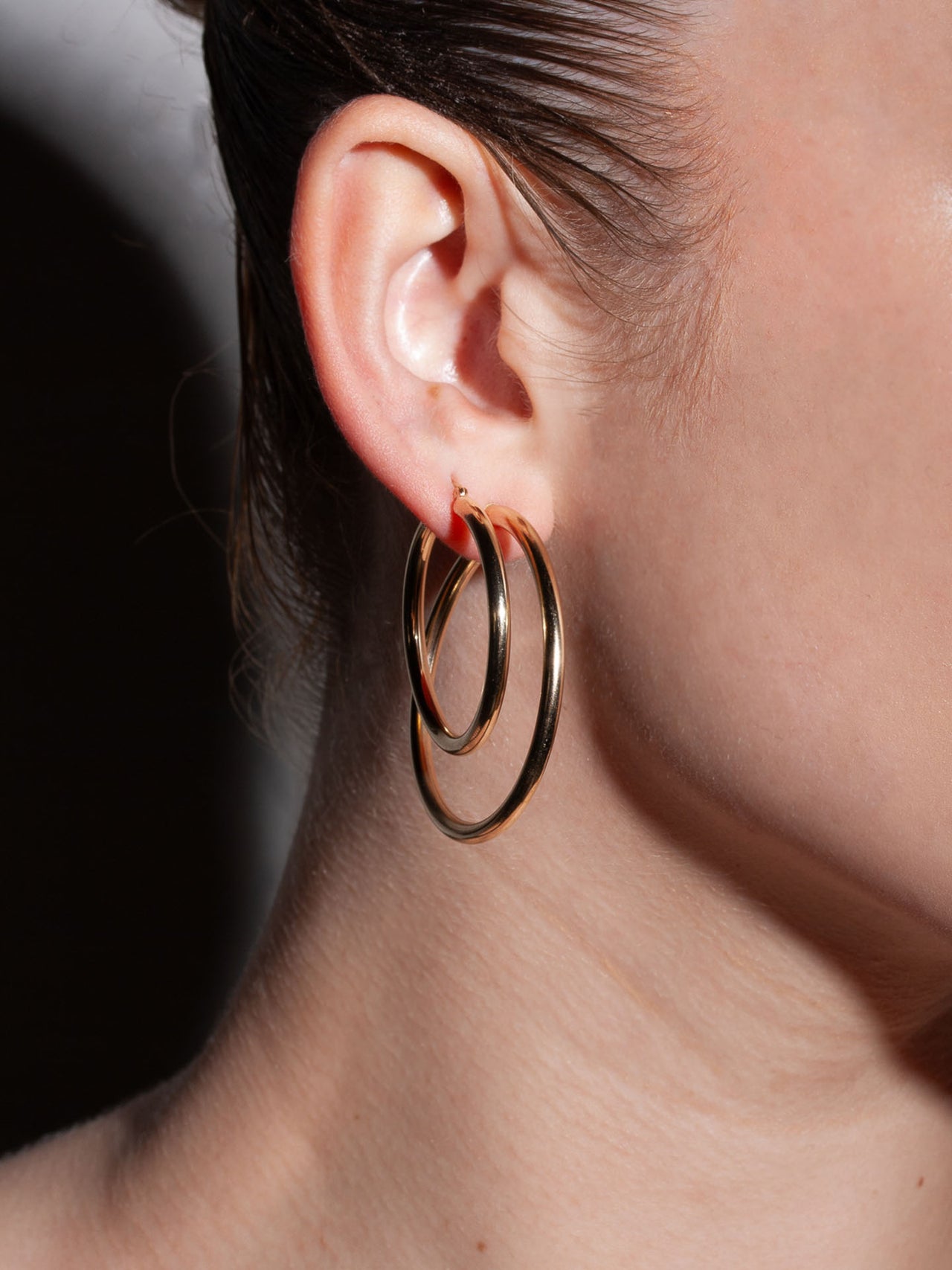 Annika 14kt Yellow Gold Hollow Tube Hoops pictured on models ear along with the Natasha Hoops.