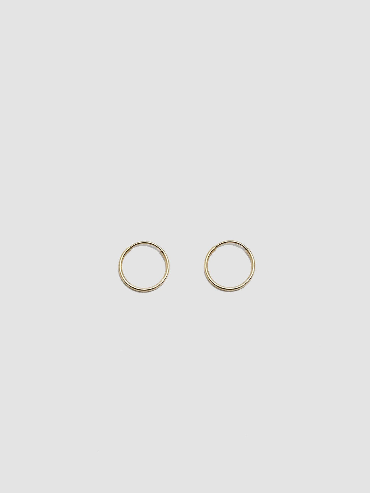 Product shot of the Valle Hoops (14Kt Yellow Gold Hoops 0.47” Diameter Thickness: 1mm) Background: Grey Backdrop