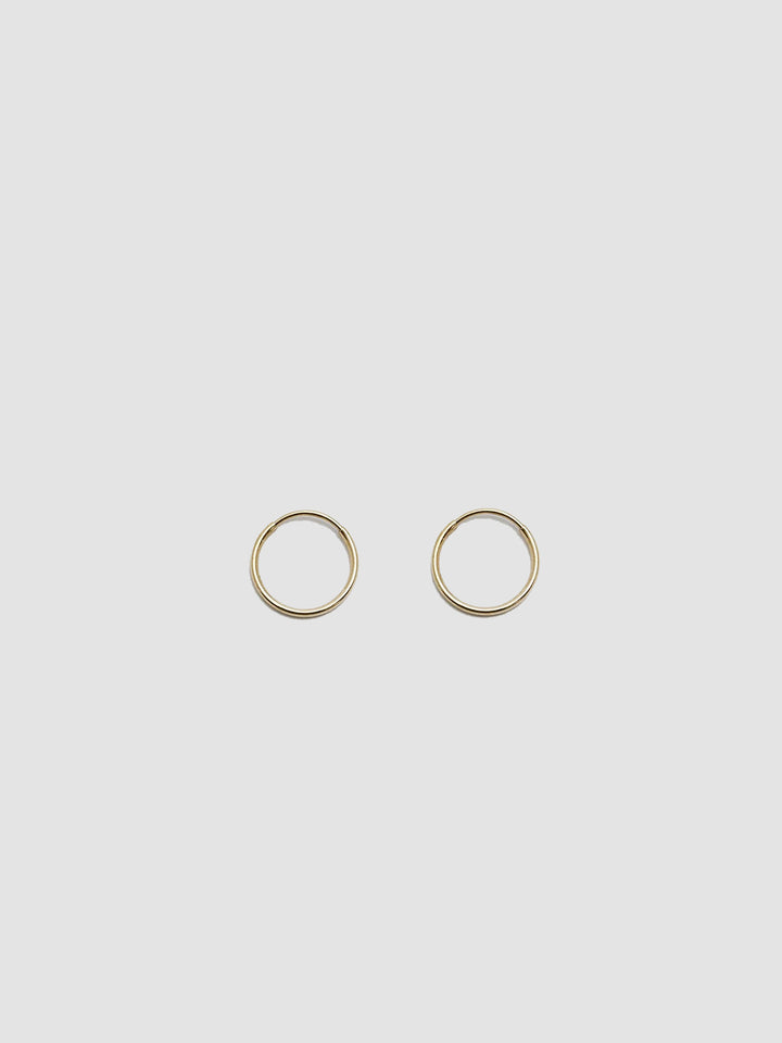 Product shot of the Valle Hoops (14Kt Yellow Gold Hoops 0.47” Diameter Thickness: 1mm) Background: Grey Backdrop