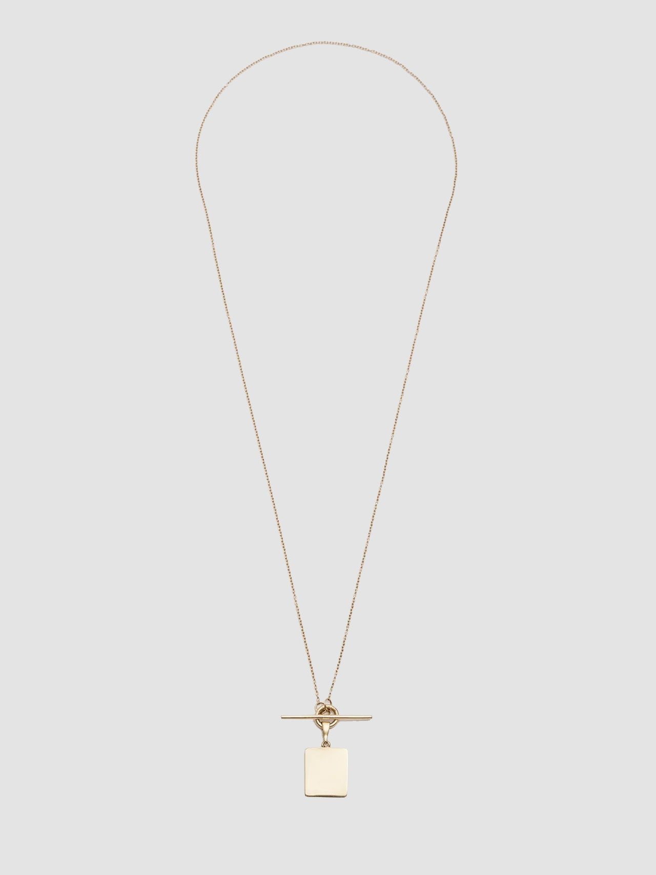 Gold necklace with a pendant on a light gray background