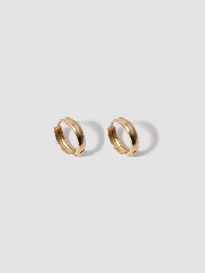 Gold hoop earrings on a light gray background