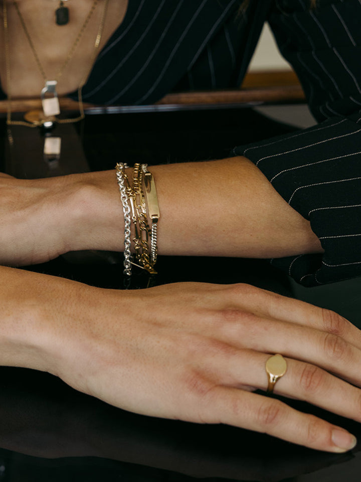 Mini Watts ID Bracelet pictured on models wrist. Layered with other bracelets.