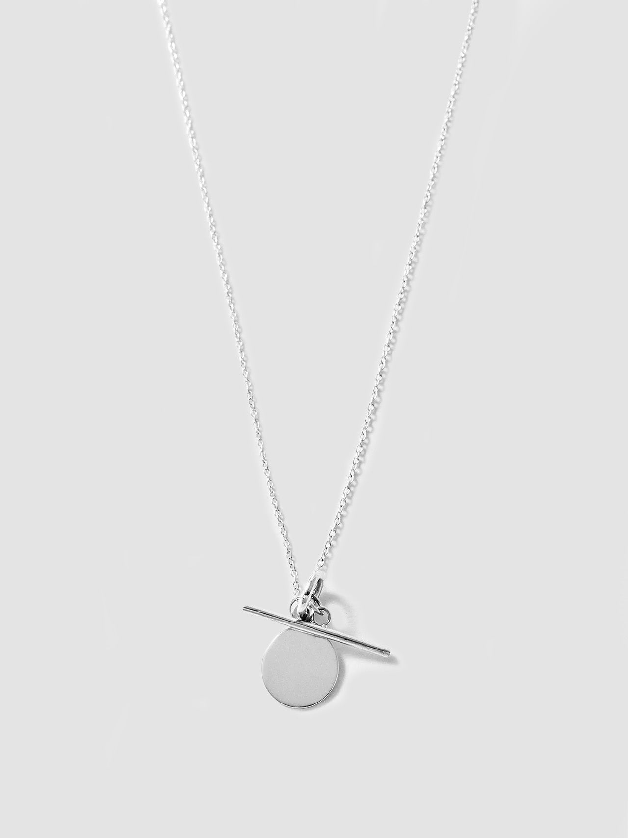 Silver necklace with a round pendant on a light gray background
