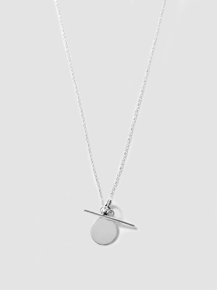 Silver necklace with a round pendant on a light gray background