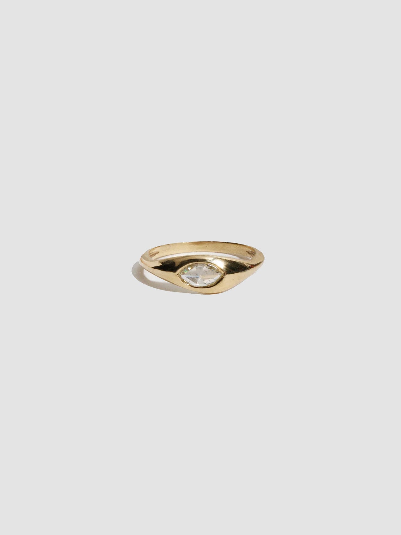 Gold ring with a diamond on a light gray background