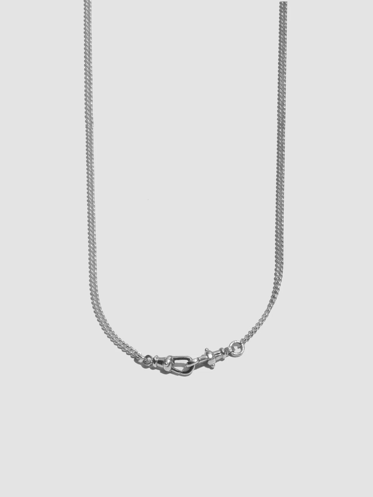 Silver necklace with a clasp on a light gray background