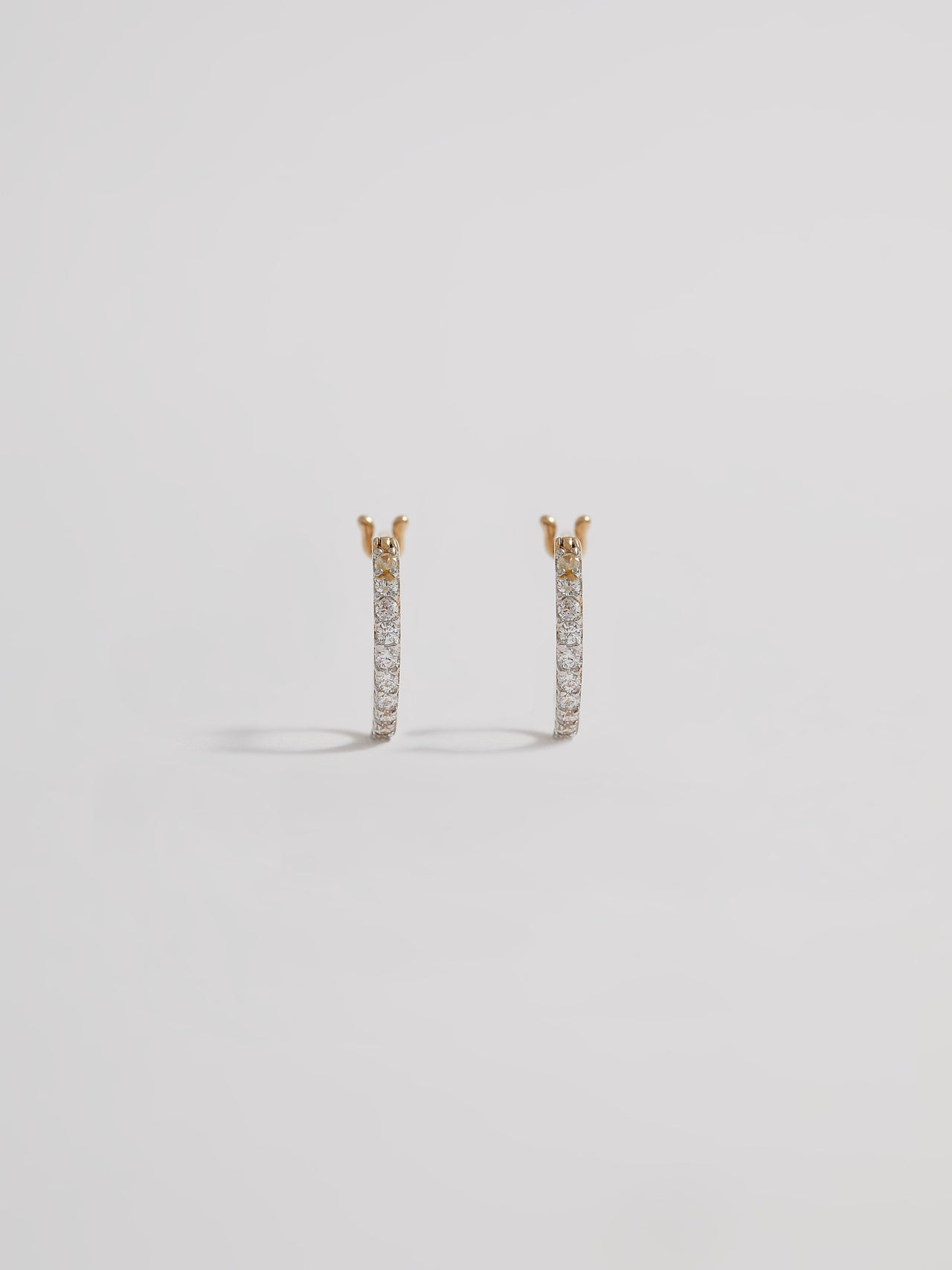 Product shot of the Petite Pave Huggies (14KT Yellow Gold 10mm Diameter 1.1mm CZ) Background: Grey backdrop