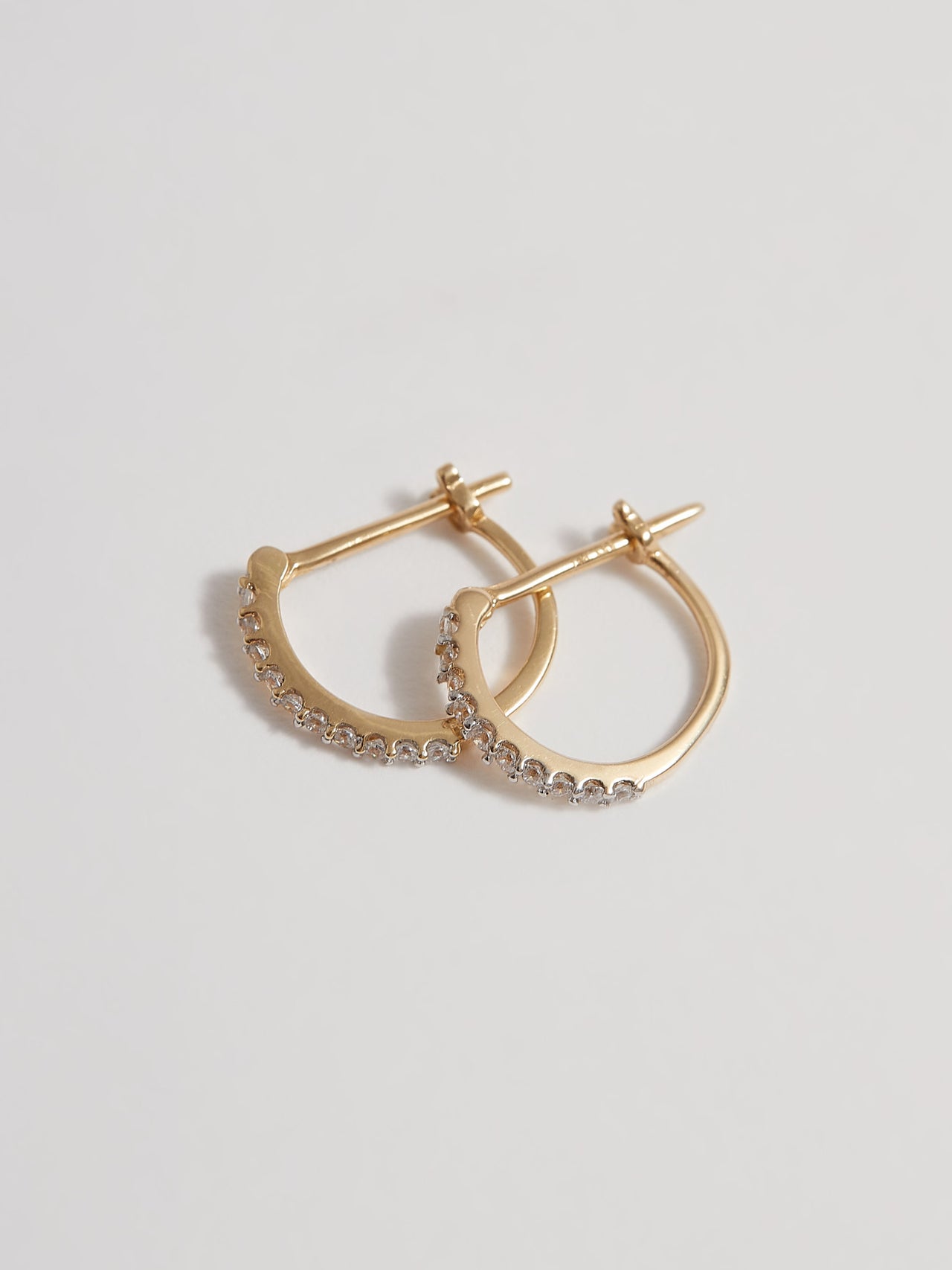 Product shot of the Petite Pave Huggies (14KT Yellow Gold 10mm Diameter 1.1mm CZ) Background: Grey backdrop