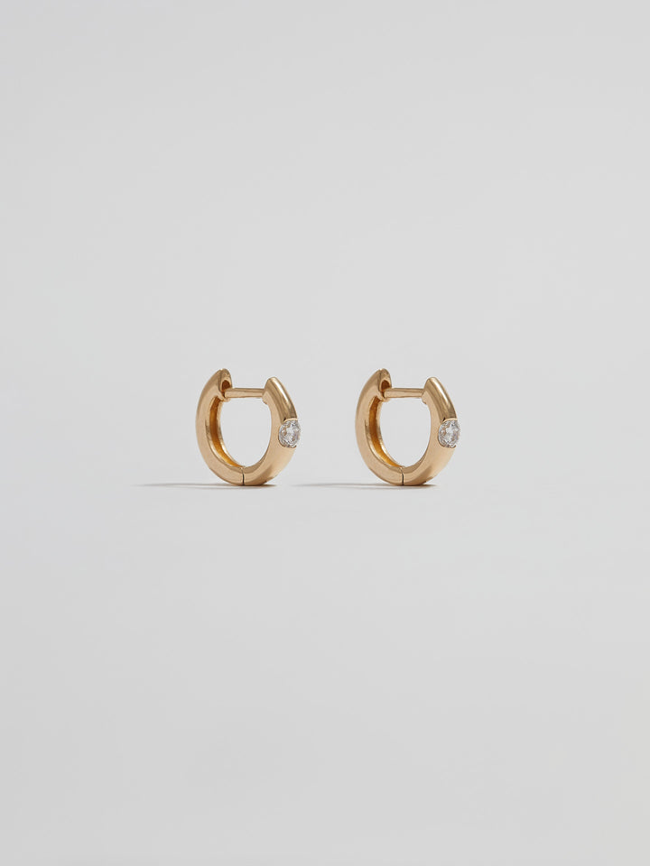 Product shot of the Solo Sparkle Huggies (14kt Yellow Gold 7.7mm Diameter 1.7mm Wide 1.11gr) Background: Grey Backdrop