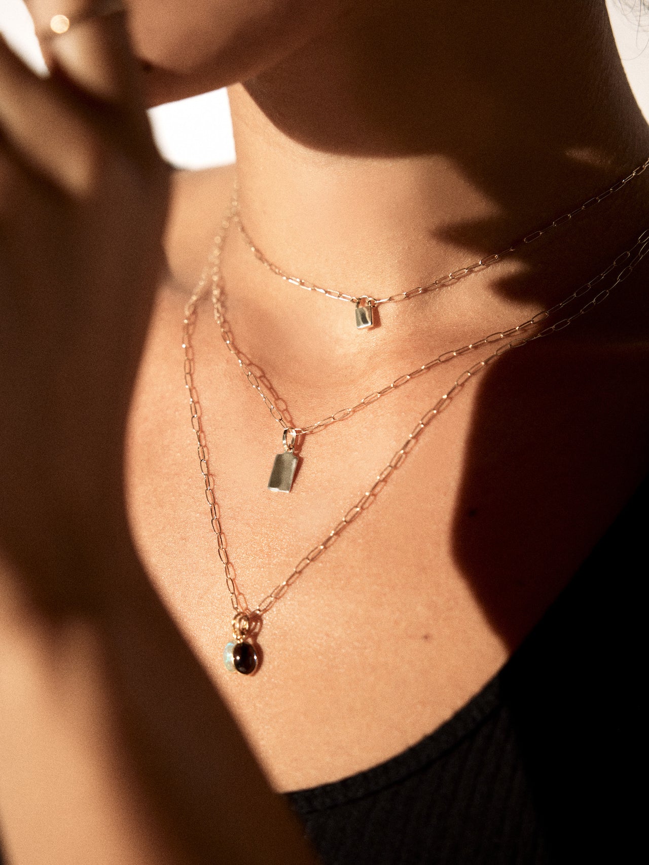 on model imagery of klint id charm pendant. three necklaces with pendants pictured. 