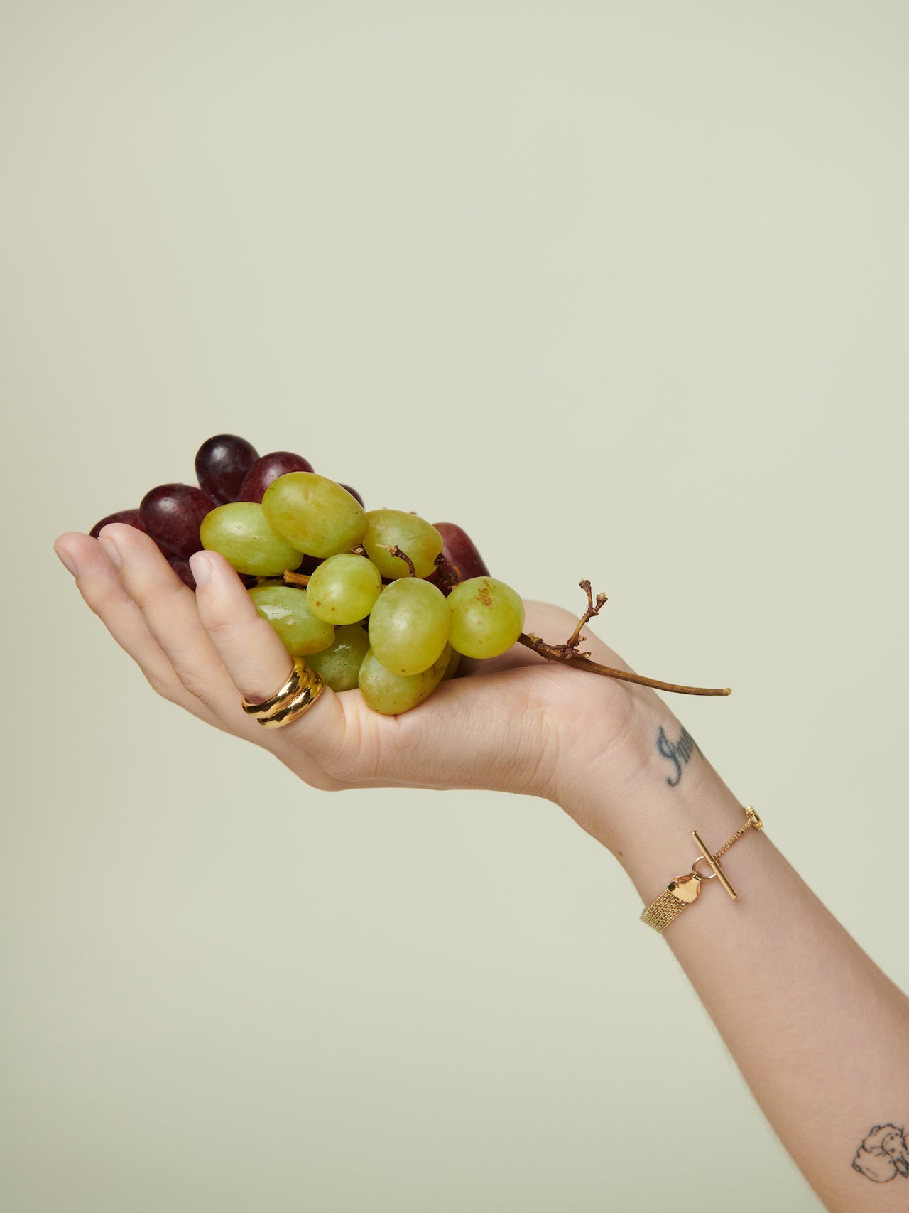Hand pictured holding grapes, wearing the Double Puff Band and Vermeil Bizmark Chain Bracelet on wrist. 