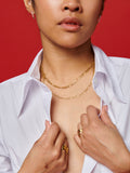 14kt Yellow Gold Hollow Figaro Chain pictured on model. Red background. 