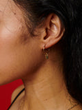 14kt Yellow Gold Padlock Earring Charm pictured on Mini Infinity Hoops. Red Background.