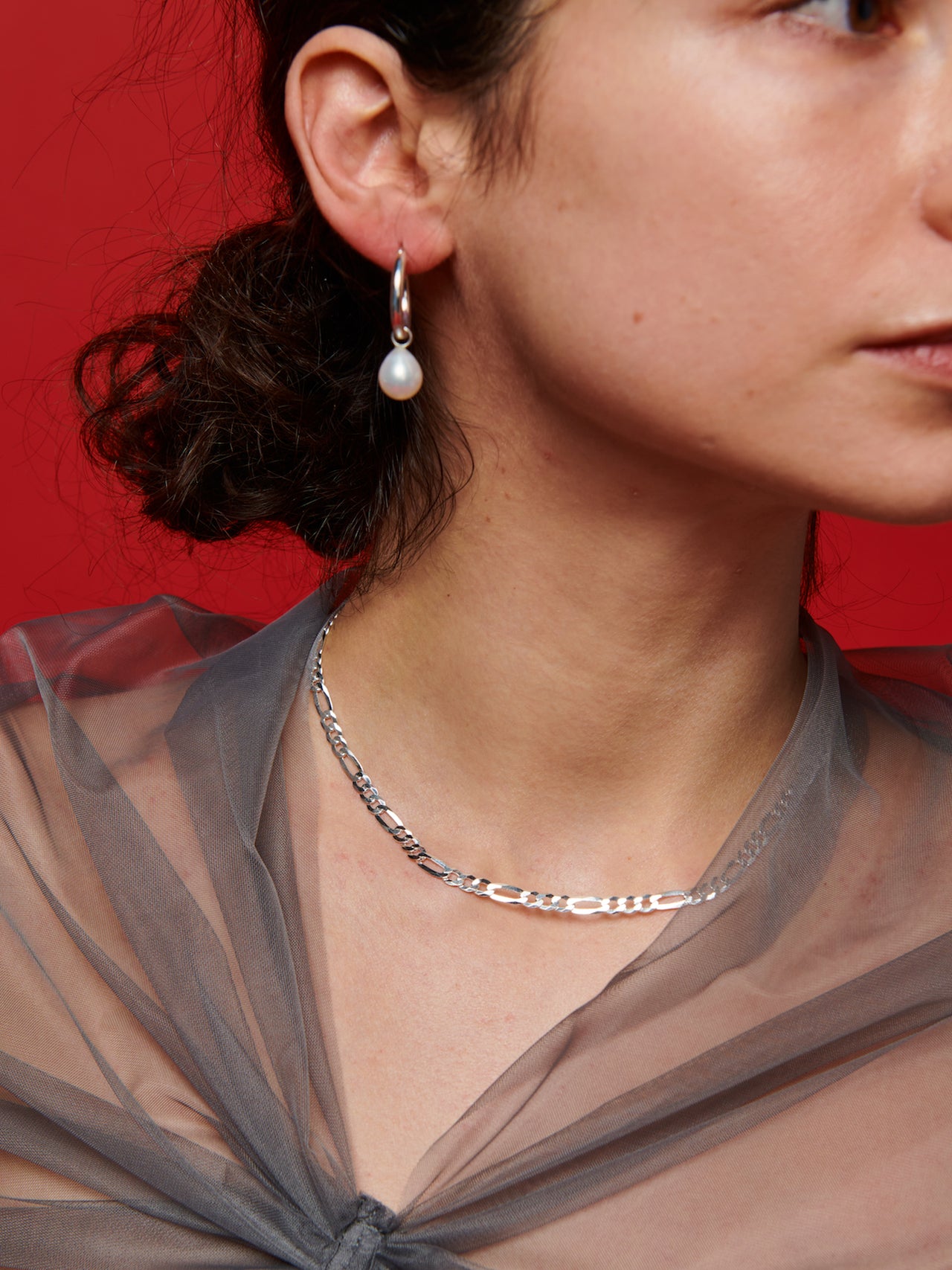 Pearl Charm Hoops pictured on model. Red background. 