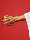 Vermeil ID Tennis Bracelet pictured on models wrist. Red background.
