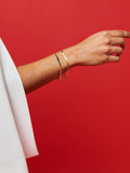 14kt Gold ID Havana Bracelet pictured on models wrist. Red background.